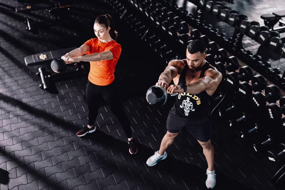 Top view of a man and woman exercising by lifting a kettlebell